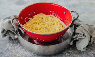 We drain the cooked pasta through a colander, but do not rinse it with water, but mix it with a tablespoon of olive oil.