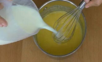 Next, gradually pour in the milk, constantly stirring the mixture with a whisk.