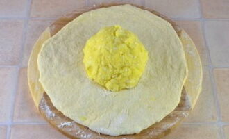 Abaisser le produit préparé en une galette et déposer au centre une boule de pommes de terre et de fromage.