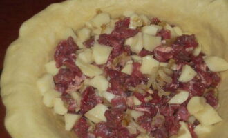 After proofing, the dough is kneaded again and divided into two unequal parts. Most of it is rolled out into a flat cake and placed in a greased baking dish. The prepared filling is laid out on the dough.