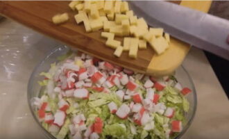 Finely chop the peeled clove of garlic with a knife. The cheese is cut into cubes.