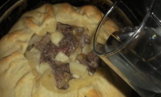 The dough around the filling is slightly wrapped like a large whitewash. The filling is covered with a lid made from the rolled out smaller part of the dough. The formed pie is placed in the oven preheated to 180 degrees for 1 hour. After an hour of baking, the lid is removed and any broth is poured into the middle of the pie, which will make the pie soft. Baking continues for another 30 minutes. The baked meat and potato pie is cooled slightly and served. Bon appetit!