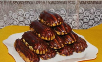 Use uma seringa para encher éclairs frios com creme e mergulhe as pontas no chocolate ao leite derretido. Bom apetite!