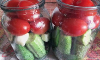 Tomato dicucuk dengan pencungkil gigi dan diletakkan di atas timun dengan bawang putih.