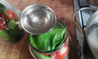 Tomato ditutup dengan daun lobak pedas. Kemudian sayur-sayuran di dalam balang dituangkan dengan air mendidih, ditutup dengan penutup dan dibiarkan selama 10 minit.