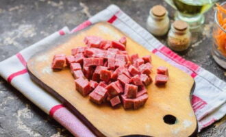 Hvordan tilbereder man en salat med bønner, pølse og croutoner? Skær din yndlingsrøgpølse i små tern.