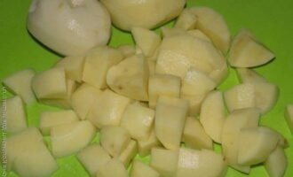 Gupitin ang mga peeled na tubers ng patatas sa mga cube at ibuhos sa isang kasirola.