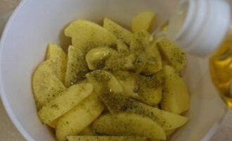 Then pour vegetable oil into the potatoes and mix everything so that the slices are evenly coated with oil.