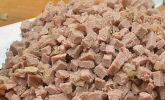 A piece of pork is boiled in advance in broth with the addition of salt and any spices. Boiled pork is cut into small cubes. The broth is left.