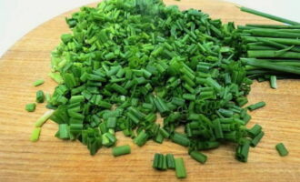 As penas da cebola verde são lavadas com água fria, secas com guardanapo e cortadas em pequenos pedaços.