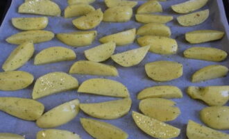 Line a baking tray with a piece of baking paper and place the potato wedges on it in an even layer. 