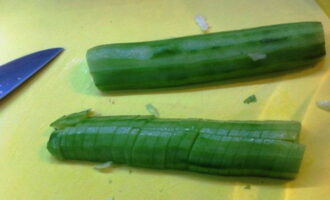 Rinse the long cucumber with cold water, partially remove the peel with a vegetable peeler and cut it into thin pieces of arbitrary shape. Transfer the cucumber slices to the cabbage.