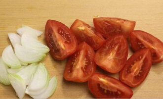 Tomaten en uien worden heel eenvoudig voor de winter bereid. Spoel de voor bereiding geselecteerde tomaten af ​​onder stromend water. Snijd ze vervolgens in grote plakjes en verwijder de stengels. Schil de uien en snijd ze in halve ringen.Spoel de greens af