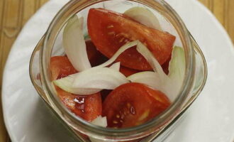 Then compactly place the tomato slices in the jar, distributing the rest of the onion between them. Shake the jar of vegetables a couple of times so that the pieces of vegetables settle more tightly.