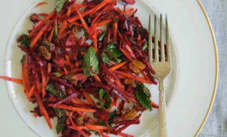 Metti l'insalata cruda di barbabietola rossa e carota preparata su piatti porzionati, servi e potrai goderti l'insolita combinazione di gusto e aroma di questo piatto. Buon appetito!