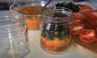 Sterilize small jars and lids in any way. Cut clean tomatoes into large slices. Place tomato slices, vegetable mass and chopped herbs in sterile jars in layers and compactly.