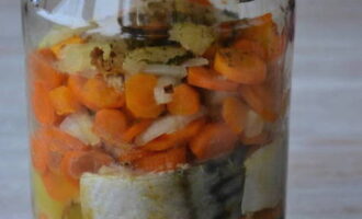 Turn on the oven at 160 degrees. Bake mackerel in a jar with vegetables for 1 hour. Remove the jar from the oven and seal it tightly with a sterilized lid. Then cover it with a terry towel for at least 6 hours and transfer it to a cool place for storage.