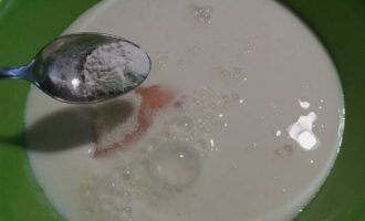 Kemudian masukkan soda penaik ke dalam susu curdled, kerana ia adalah apa yang akan membuat doh berbuih.