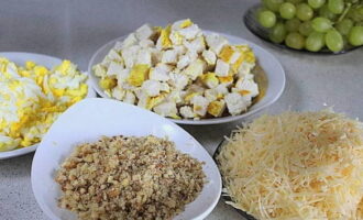 Tagliare il filetto raffreddato a cubetti. Macinare le uova sode e il formaggio su una grattugia grossa. Macinare le noci in briciole medie usando un frullatore. Separare gli acini dal grappolo, tagliarli a metà ed eliminare i semi. In una tazza, mescolare la maionese con lo yogurt.