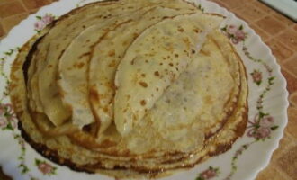 Após 15 minutos, comece a assar panquecas. O processo de cozimento é igual ao das panquecas normais. Unte a frigideira com óleo antes da primeira panqueca. Coloque as panquecas finas assadas com creme de leite furado em um prato, unte cada panqueca com manteiga e você pode servir. Bom apetite!