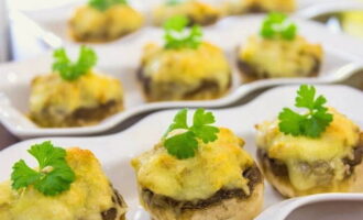 Fertig sind köstliche und appetitliche gefüllte Champignons. Servieren Sie sie an den Tisch und genießen Sie!