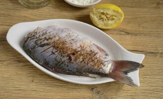 Pour lemon juice and sprinkle with spices for fish. Rub the spices thoroughly with massage movements.