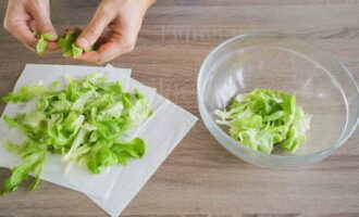 Spülen Sie die Salatblätter unter Wasser ab und legen Sie sie auf Papiertücher, um überschüssige Feuchtigkeit zu entfernen. Zerreißen Sie die Blätter mit den Händen und geben Sie sie in eine Salatschüssel.