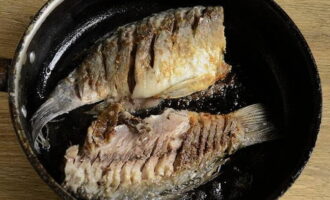 Heat the frying pan over low heat in advance. Pour in the oil you used to fry with. Carefully place the crucian carp. Increase heat to medium. Fry until golden brown on both sides. An appetizing crust should form, and only then should you turn it over.