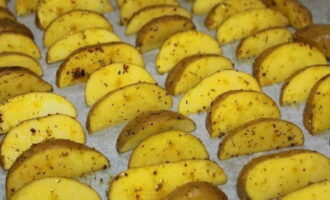 Cover a baking sheet with parchment. Place prepared potato wedges on it. Place the dough in an oven preheated to 180 degrees for 20-25 minutes. 