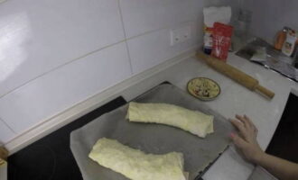 Em seguida, enrole cuidadosamente dois rolinhos com as mãos e coloque-os em uma assadeira forrada com papel. Unte a superfície dos produtos com gema. Asse o strudel de massa folhada com maçãs em forno pré-aquecido a 180 graus por 40 minutos até dourar. Decore o strudel assado a seu gosto com açúcar de confeiteiro ou nozes e sirva com chá. Bom apetite!