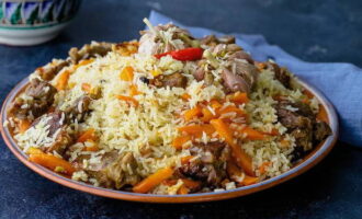 Coloque o pilaf pronto em uma bela travessa. Retire a tampa e o prato, retire com cuidado o alho, cubra com um prato maior e vire com cuidado. O arroz ficará por baixo e a carne e os legumes por cima, decore com cabeças de alho e sirva. Bom apetite!