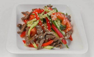 Salad cerah dengan daging, lada benggala dan timun sudah siap!