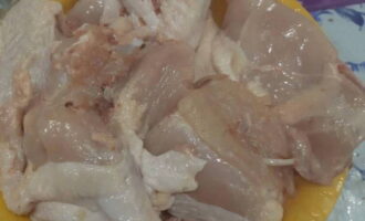 Sciacquare bene il pollo sotto l'acqua e dividerlo in porzioni.