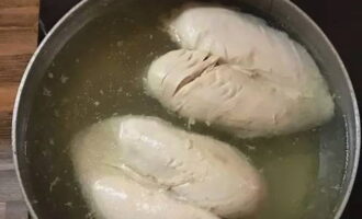 Die Hähnchenbrüste waschen, die Haut entfernen und in eine Pfanne geben. Mit Wasser füllen. Auf den Herd stellen und bei mittlerer Temperatur zum Kochen bringen, den Schaum mit einem Schaumlöffel abschöpfen. Den Deckel schließen und bei schwacher Hitze etwa eine Stunde garen. Lassen Sie das fertige Fleisch in der Brühe, bis es vollständig abgekühlt ist.