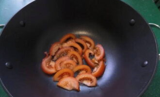 Place slices of one tomato in a cauldron with a non-stick coating.