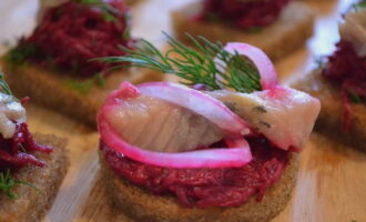 Lyse smørbrød på svart brød med sild og rødbeter er klare. Du kan servere den til bordet!