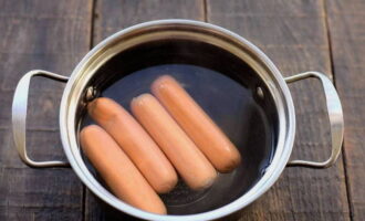 Immerse the peeled sausages into boiling water.