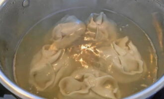 Wait until the broth boils again and reduce the temperature. Cook the manti for 10 minutes, covering the pan with a lid.