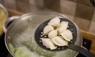 Using a slotted spoon, gradually add the dumplings into the pan.