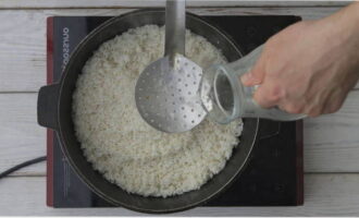 Lave novamente o arroz com uma peneira e deixe escorrer o excesso de líquido. Espalhe o arroz lavado em uma camada uniforme sobre o zirvak. Coloque o fogo no máximo e, com uma escumadeira, acrescente água fervente até que o arroz cubra 3 centímetros.