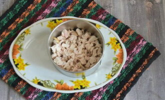 Ora iniziate ad assemblare l'insalata. Posizionate un anello da cucina sul piatto in cui servirete l'insalata. Disporre la carne di pollo sul fondo.