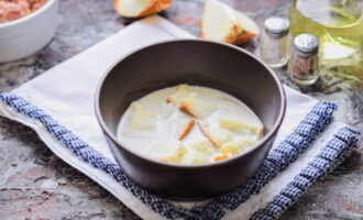 Füllen Sie ein Stück Weißbrot mit Milch in eine separate Schüssel und lassen Sie es einige Minuten einweichen.