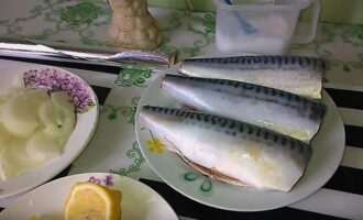 Remova a cabeça e a cauda, ​​​​as entranhas e principalmente a película preta das carcaças, cortando a barriga longitudinalmente. Em seguida, enxágue bem o peixe em água corrente. Descasque e corte a cebola ao meio rodelas. Lave o limão e corte-o com a casca em rodelas finas.