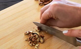 Macinare le noci in briciole grossolane utilizzando qualsiasi metodo. Dividete le uova sode in albumi e tuorli e tritatele singolarmente su una grattugia grossa. Macinare un pezzo di formaggio a pasta dura allo stesso modo.