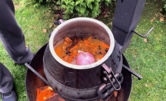 Then put the chopped carrots, a head of unpeeled garlic with a pod of hot pepper into the cauldron. Sprinkle everything with salt and pilaf seasoning to your taste. Pour 2-3 glasses of clean water into the cauldron, close the lid and cook these ingredients, that is, zirvak, for 15 minutes.