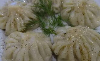 Using a slotted spoon, carefully transfer the boiled khinkali from the pan into portioned plates, sprinkle with ground black pepper and finely chopped herbs. Serve the dish to the table. Bon appetit!