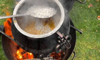 Rinse the rice several times with cold water.Then lay it in an even layer on top of the meat and place the head of garlic in the middle of the rice. Add another half glass of clean water to the cauldron and close the lid. Cook pilaf for another 20 minutes.