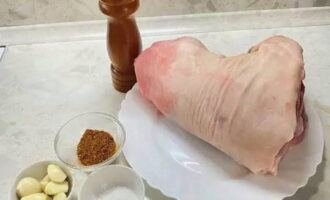 Take a fairly heavy chilled or frozen pork knuckle. If necessary, defrost, wash under the tap and dry with napkins. Remove the top layer from the garlic cloves. Gather your favorite spices. I use meat seasonings most often, and Italian herbs are also great.