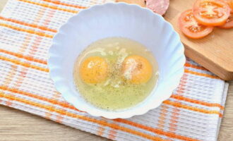 Break the egg into a deep bowl. Add salt and ground black pepper to it to taste.