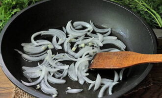 Heat the oil in a frying pan and saute the onion half rings and garlic cloves for several minutes over medium heat.